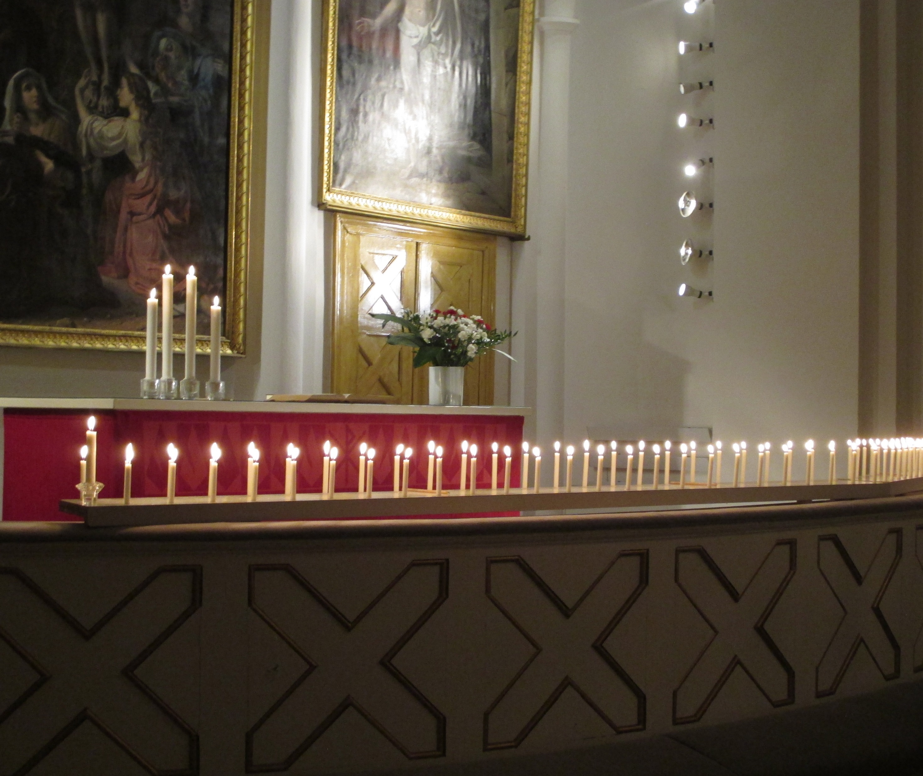 sytytettyjen pienten kynttilöiden rivistö kirkon alttarikaiteella