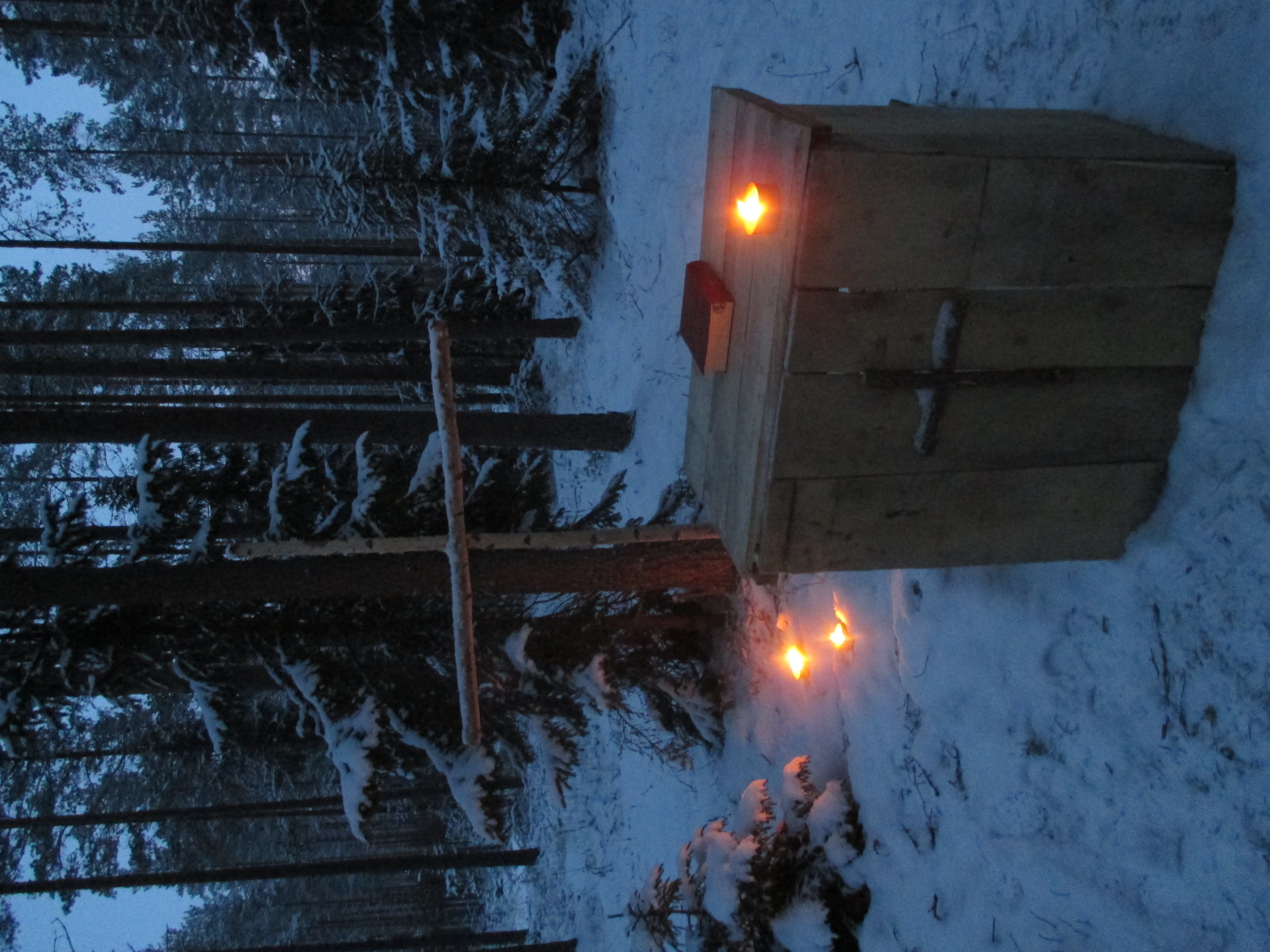 puinen pöytä ja risti hämärässä, lumisessa metsässä
