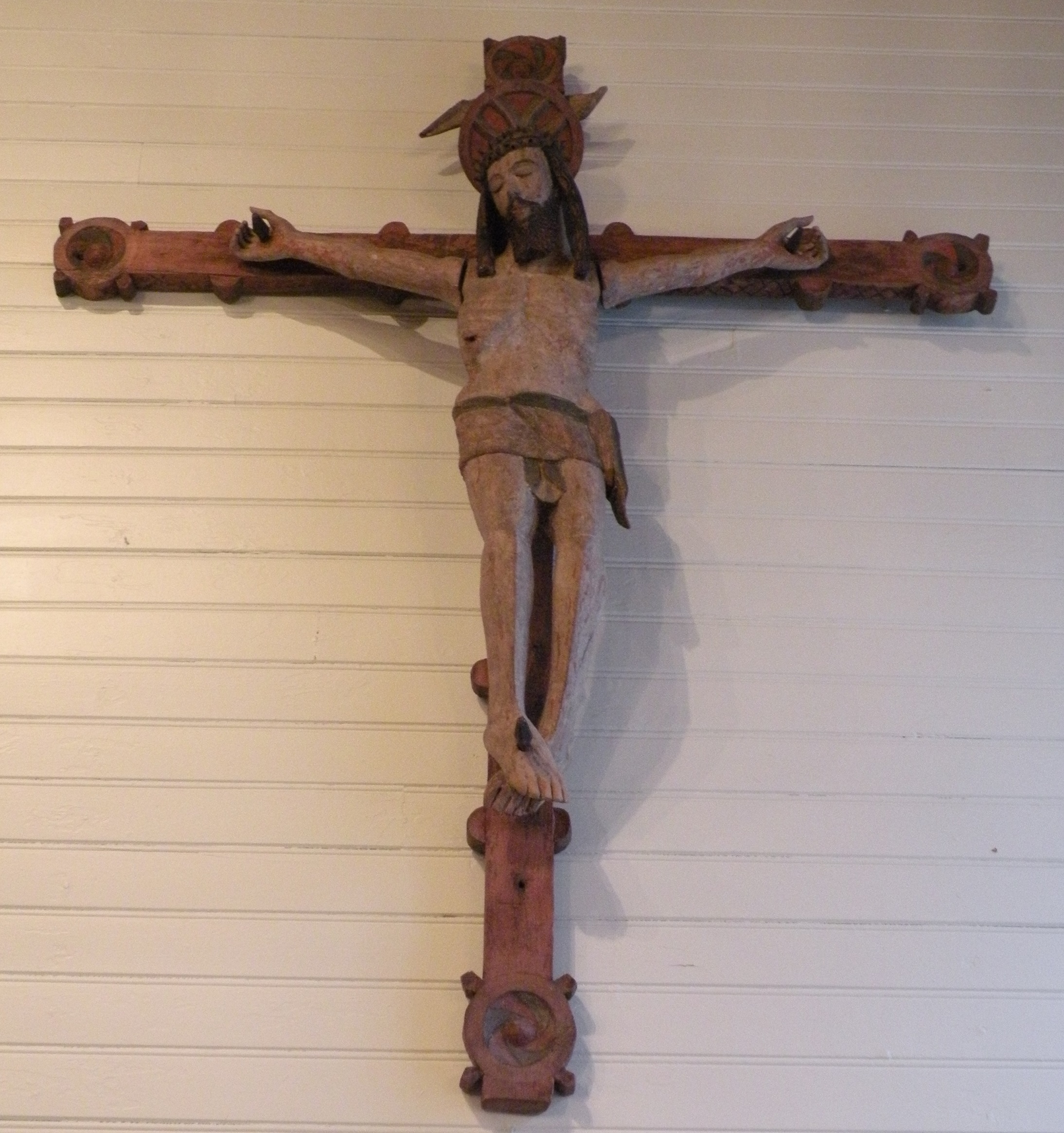 puinen ristiinnaulittua esittävä veistos kirkon seinällä