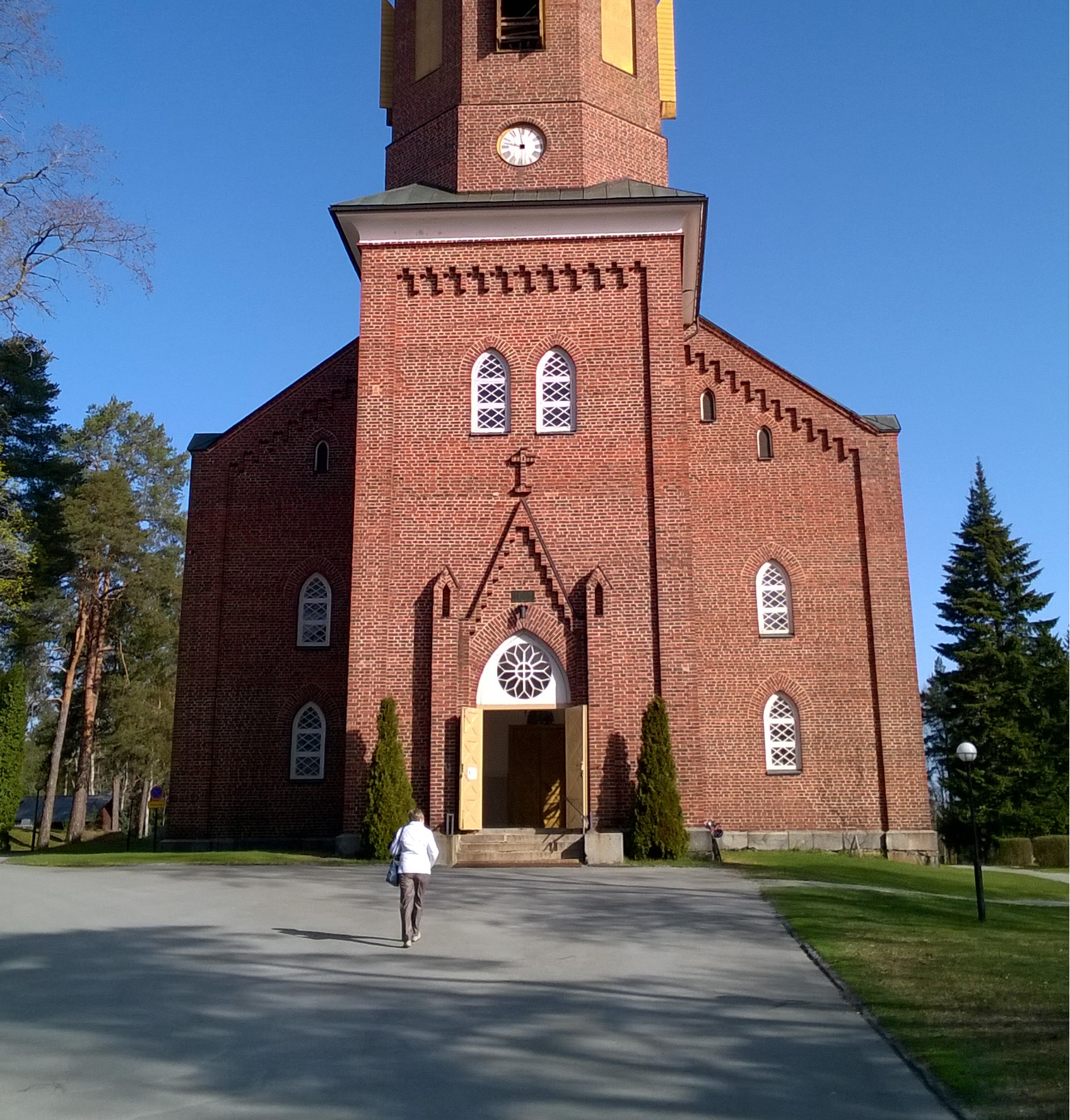 kirkko avoinna yksityistä rukousta ja hiljentymistä varten Kulkija astelee aurinkoisena päivänä kohti Hattulan kirkon avointa ovea.